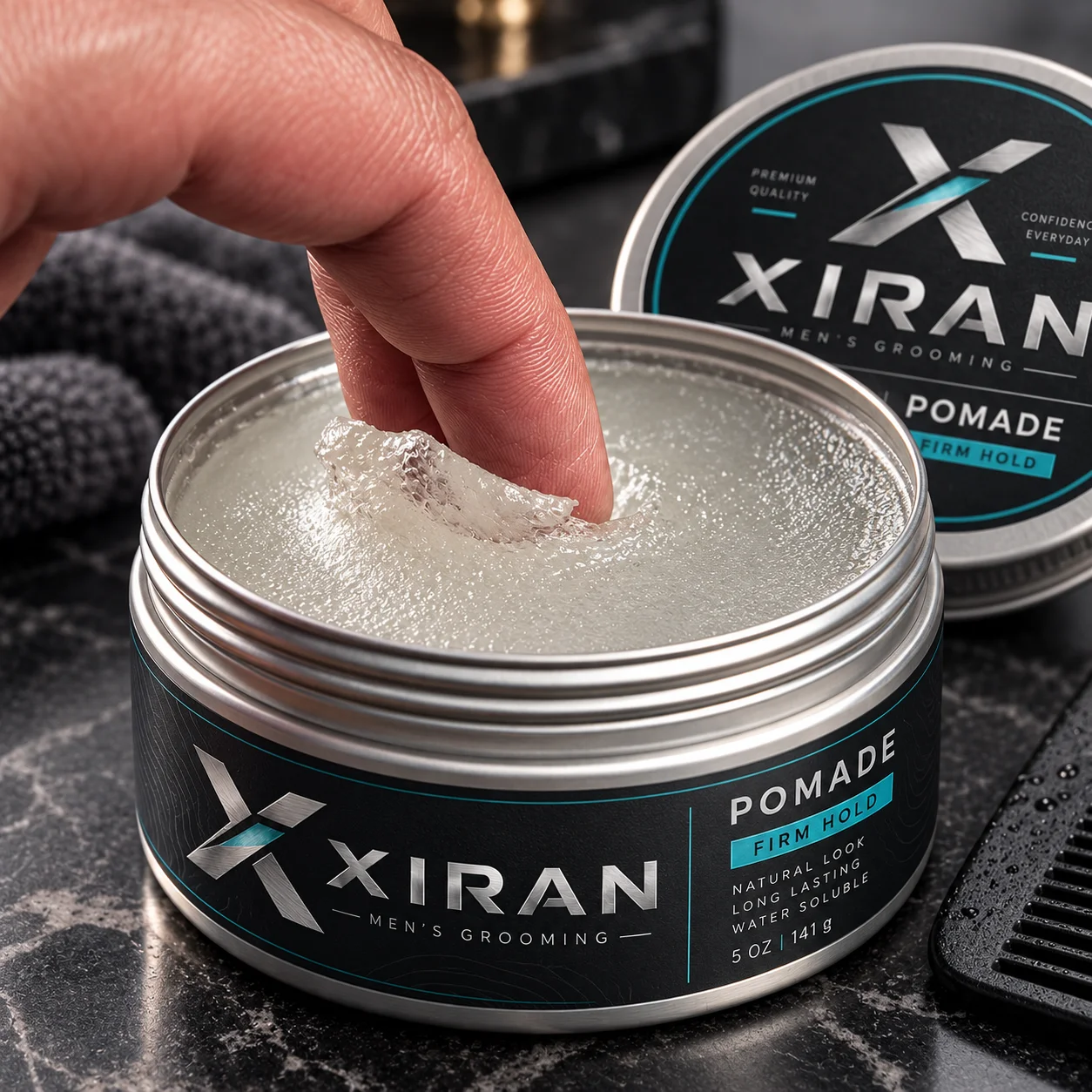 Close-up of a person dipping a finger into a jar of Xiran men's grooming pomade with firm hold, displayed on a dark marble surface with a comb and towel nearby.